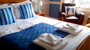 Un lit bien fait, avec une literie bleue et blanche, une couverture bleue et des serviettes pliées.