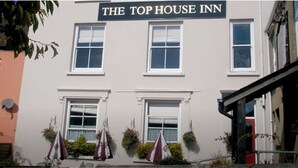 Un bâtiment sur lequel on peut lire l’inscription suivante : « THE TOP HOUSE INN ».