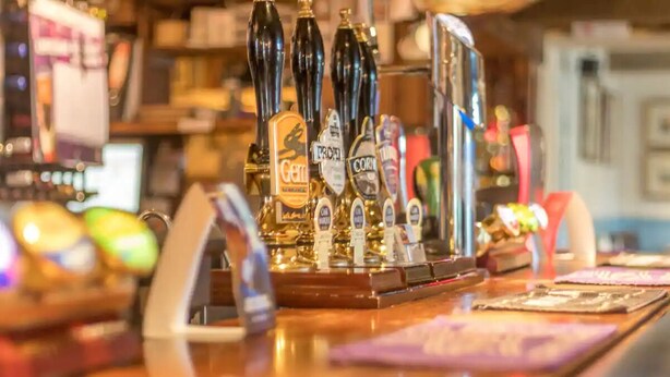 Un comptoir de bar doté de plusieurs tireuses à bière et offrant un choix de bouteilles.