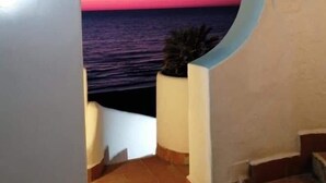 A corridor with a view of the sea at sunset through a circular archway. - Studio apartment, sea front, terrace, floor 1 (Poppy) (Anzio)