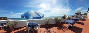 A terrace with outdoor seating, a blue umbrella, and a view of the sea. - Studio, side view of the sea, first floor (Gelsomino) (Anzio)