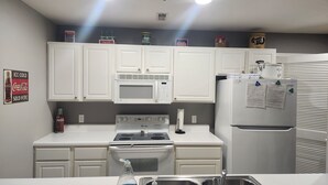 A modern kitchen with white cabinets, a microwave, stove, and refrigerator.