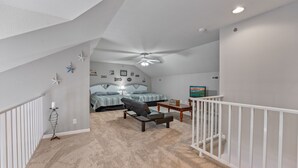 A bedroom with a bed, a chair, a desk, and a TV.