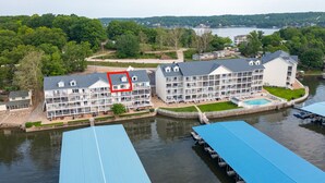 A waterfront hotel with multiple balconies, a swimming pool, and a dock with boats.