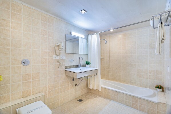 Une salle de bain avec une baignoire, un lavabo avec un miroir et des toilettes.