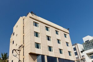 A multi-story building with a beige facade, multiple windows, and a flat roof.