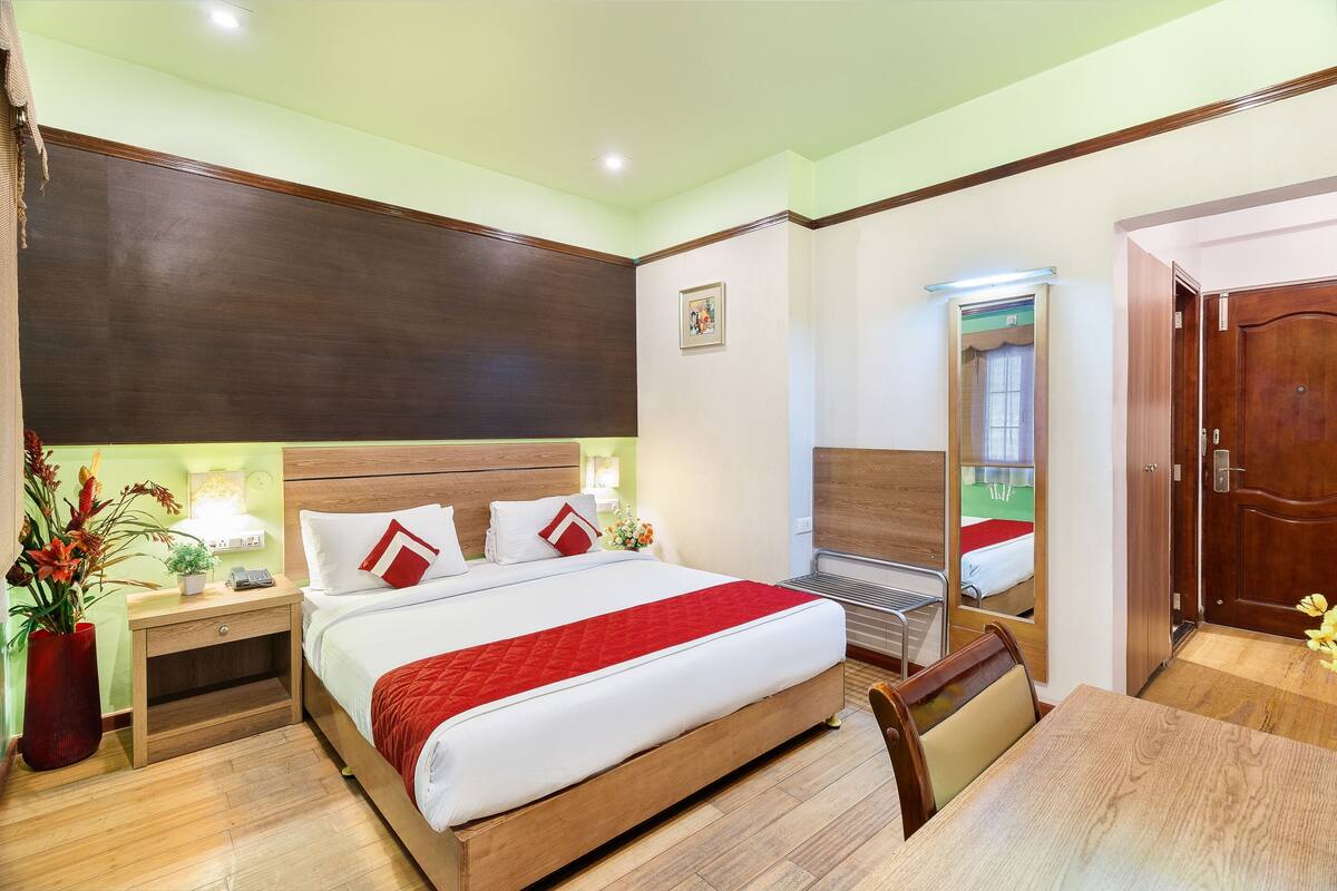 A hotel room with a large bed, bedside tables, a desk, and a mirror.