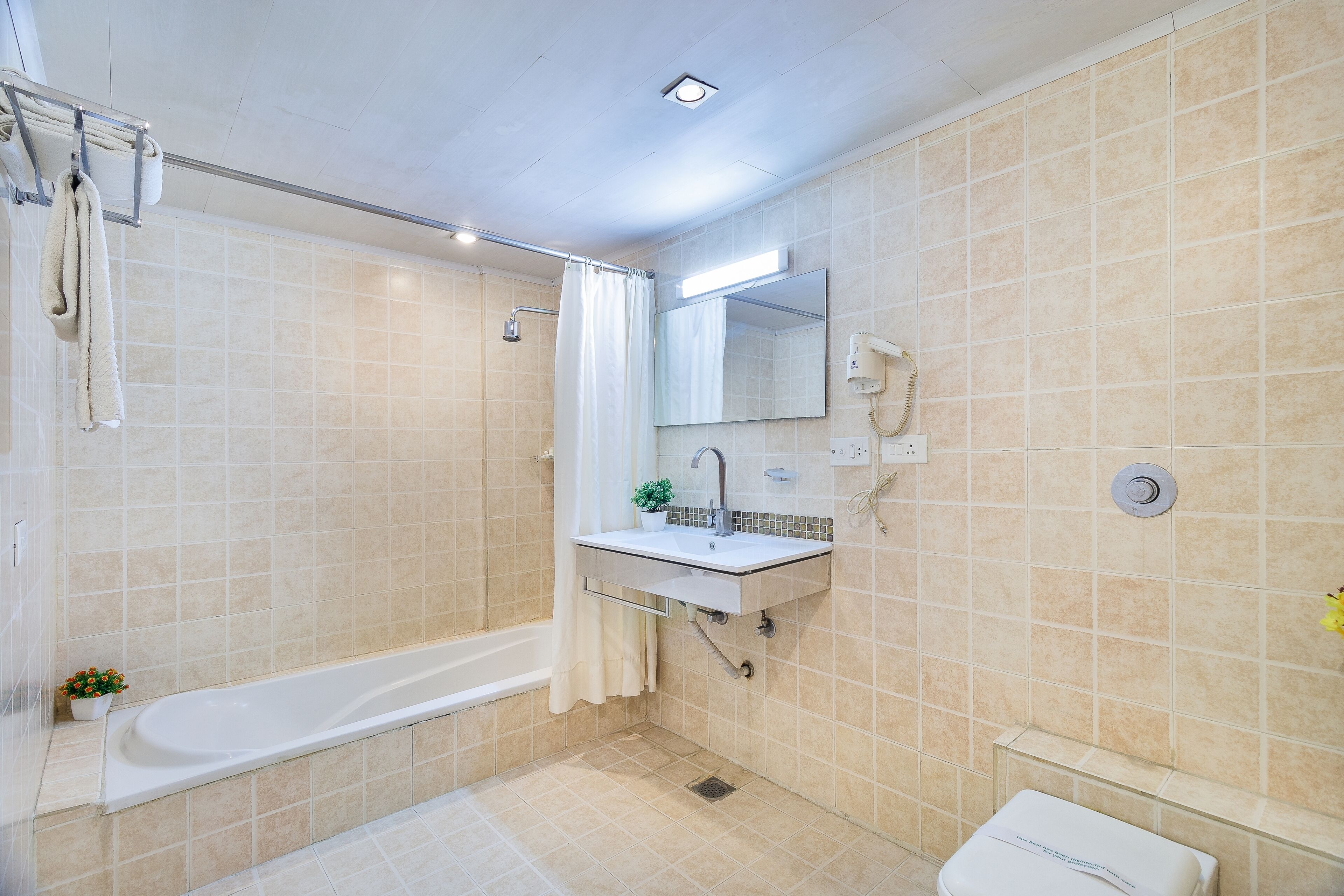 A bathroom with a bathtub, a sink, a mirror, and a toilet.