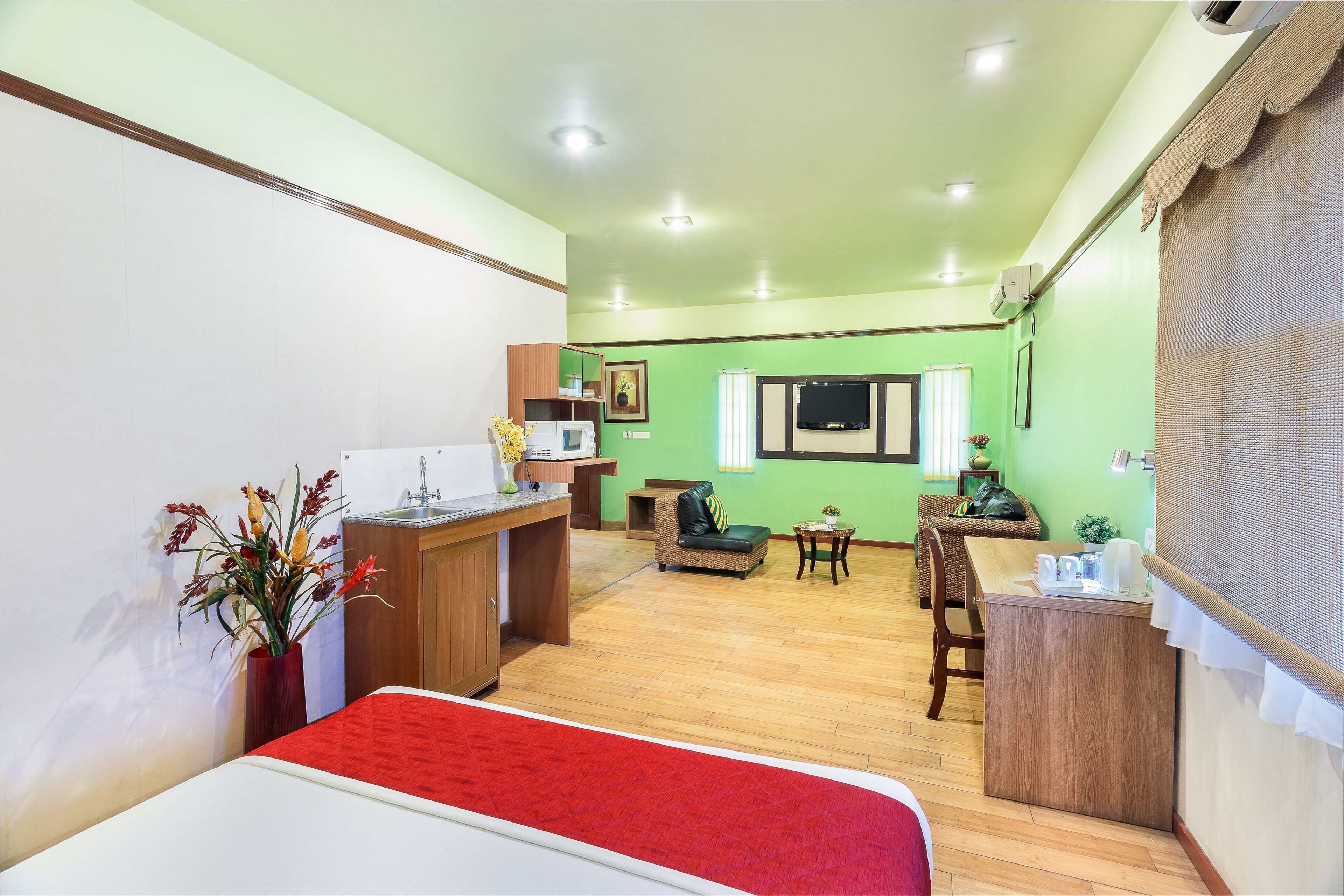 Camera d'albergo compatta con un letto, un angolo cottura, una zona pranzo con tavolo e sedie, e un salottino con divano.