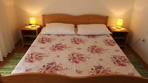 A bed with a floral bedspread, two white pillows, and two bedside lamps. - Comfortable apartment Trupec not far from the center. (Malinska)