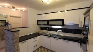 Una cocina moderna con armarios blancos, encimeras negras y una pared decorativa de piedra.