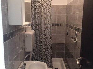 A bathroom with a shower, toilet, and sink.