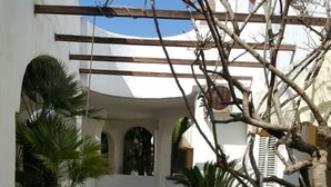 A courtyard with a tiled floor, a white wall, a wooden pergola, and a table with chairs. - Studio, terrace, first floor (Ortensia) (Anzio)