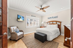 Une chambre à coucher avec un lit, une chaise, un ventilateur de plafond, une fenêtre et un panneau décoratif sur le mur.