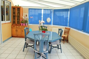 A dining area with a blue table and chairs, a wooden cabinet, and a window with blue curtains. - Large vacation home in brittany, 5 minutes walk from the beach (Lampaul-Plouarzel)