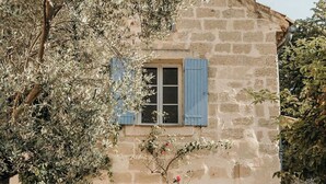 Un bâtiment en pierre avec une porte, des fenêtres et une table entourée de chaises dans la cour.
