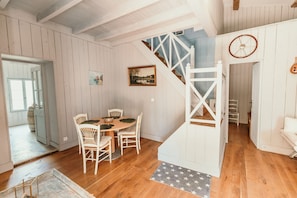 Ein Essbereich mit Holztisch und -stühlen, eine Treppe mit weißer Geländer und ein Bild an der Wand.