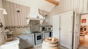 Une cuisine compacte équipée d’une cuisinière, d’un four à micro-ondes et de placards. Un tonneau en bois se trouve au centre.