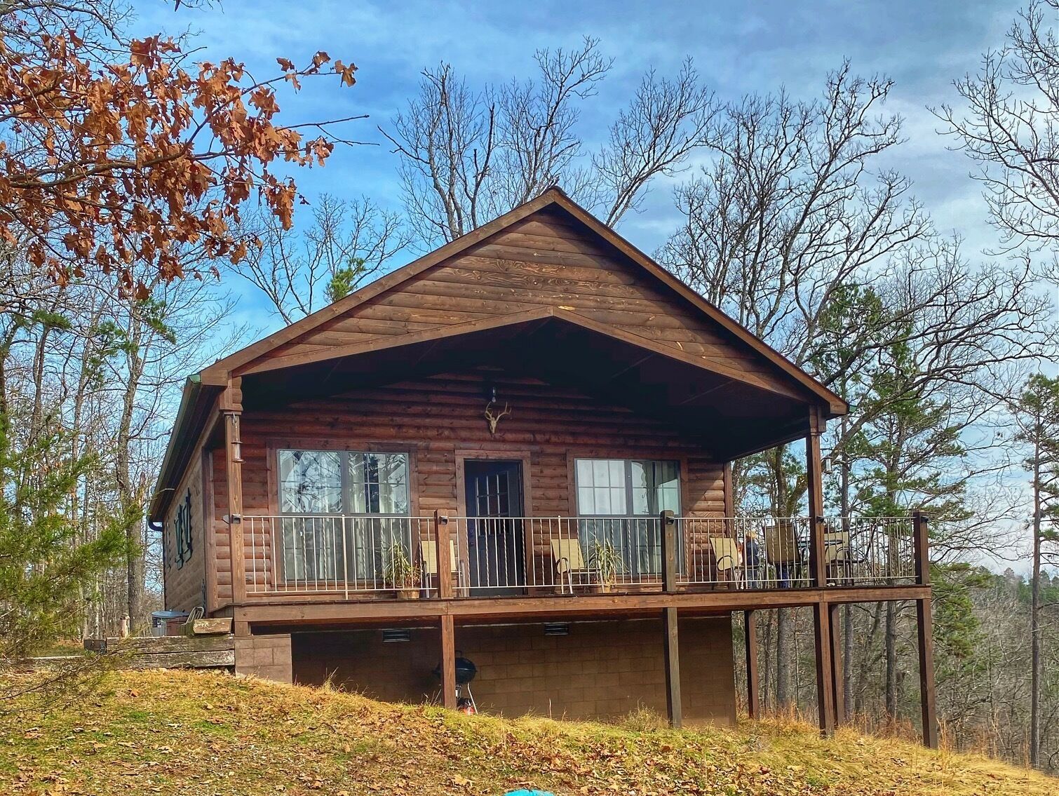 A wooden cabin with a balcony, surrounded by trees.
