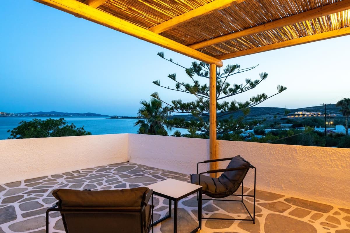 Ein Balkon mit Steinböden, zwei Stühlen und einem Tisch.