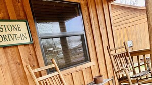 A wooden building with a 'STONE DRIVE-IN' sign, wooden rocking chairs, and a window. - Stone Drive In #305 (Mountain View)