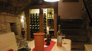 A cozy room with a stone wall, a wooden bench, a red runner, and a wine rack in the background. - Rosenhäuschen Nostalgie 4-star vacation home (Kirnsulzbach)