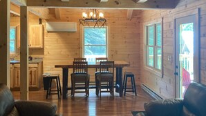 A wooden cabin interior with a dining area, kitchen, and seating space.