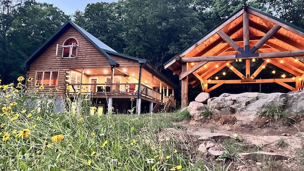 A rustic cabin with a porch and a covered area with string lights.