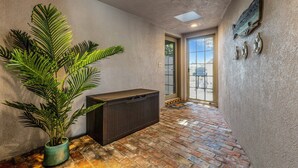 A hallway with a large potted plant, a black heater, and a door leading to a balcony. - Beach Access, Walk to village, Sunsets included (Sarasota)