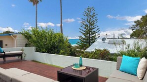 Eine Terrasse mit einer Couch, einem kleinen Tisch und Blick auf den Ozean.