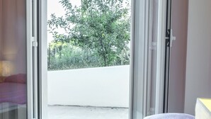 Une chambre avec un lit, une fenêtre donnant sur un espace verdoyant et une porte coulissante.