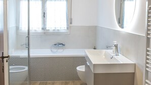 Une salle de bain moderne avec une douche à parois de verre, une baignoire, un lavabo et des toilettes.