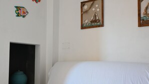 A bedroom with a bed, a wall with artwork, a small window, and a door.