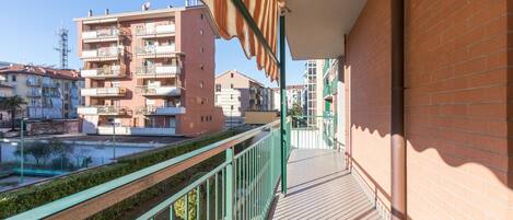 A balcony with a view of a cityscape, including multi-story buildings and a clear sky.