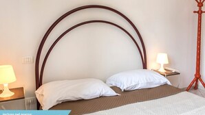 A hotel room with a bed, two bedside tables, a lamp, and a red tripod lamp. - RS315 - Marcelli, two-room apartment in a seafront residence (Marcelli)