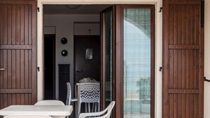 A patio with a table and chairs, a sliding glass door, and a view of the interior. - RS315 - Marcelli, two-room apartment in a seafront residence (Marcelli)