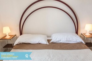 A bed with a wooden headboard, two white pillows, a brown blanket, and two bedside lamps.