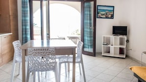 A room with a dining table, chairs, a TV, and a view through a glass door. - RS315 - Marcelli, two-room apartment in a seafront residence (Marcelli)