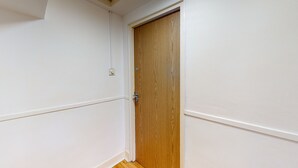Una puerta de madera cerrada en una habitación con paredes blancas y suelo de madera.