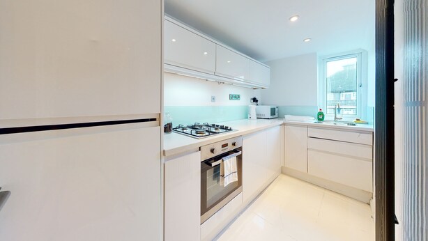 Una cocina moderna con muebles blancos, estufa a gas, horno y microondas.