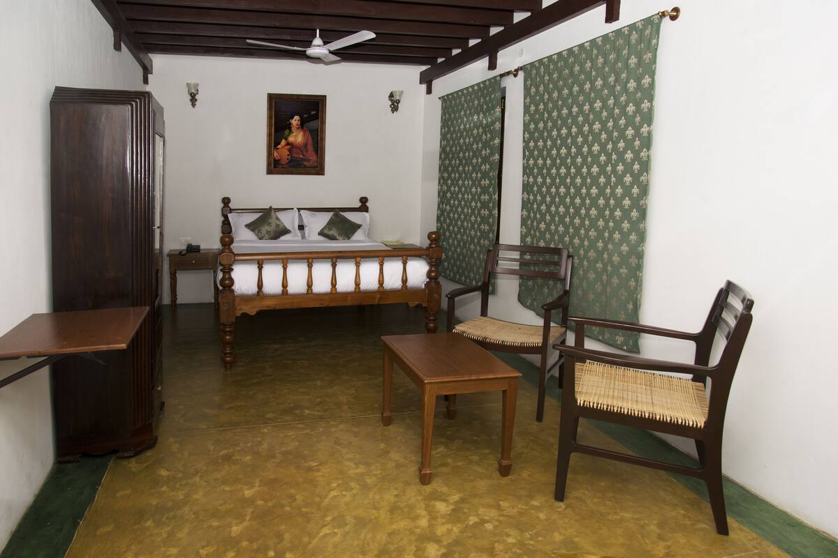 A room with a bed, wooden furniture, a ceiling fan, and patterned curtains.