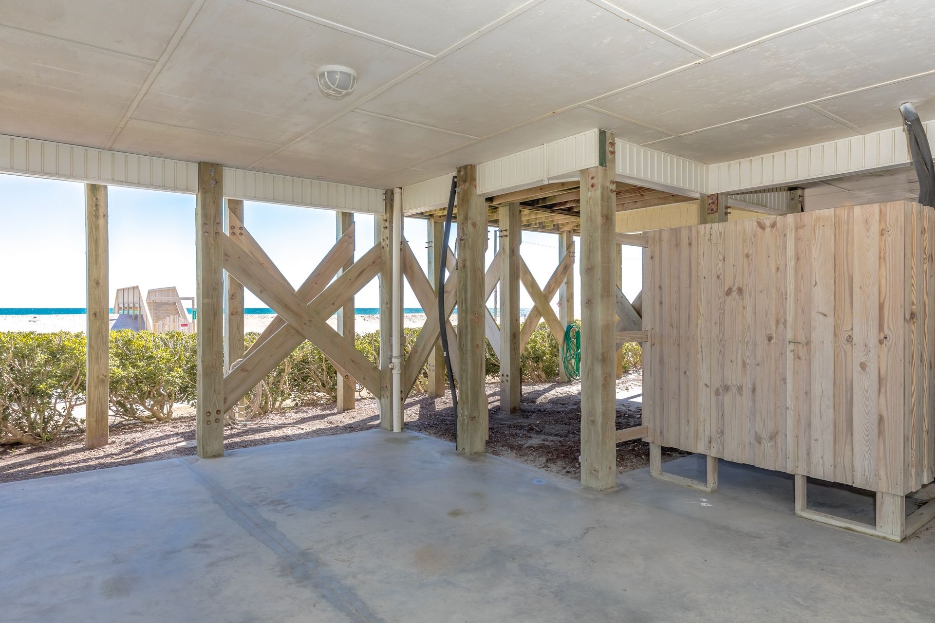 A beachside wooden structure with a concrete floor, wooden beams, and a view of the ocean.