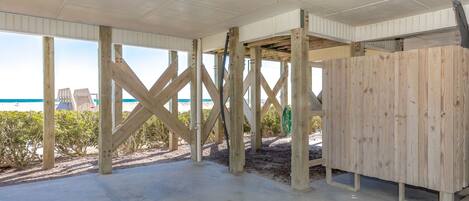 Una estructura de madera frente a la playa, con piso de concreto, vigas de madera y vista al océano.