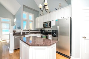 A kitchen with white cabinetry, a granite countertop, stainless steel appliances, and a large island. - Feeling TipSea - 3 BR Townhome - Amazing Ocean Views & Community Pool (Surf City)