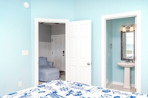 A bedroom with a bed, a door leading to a bathroom, and a light blue wall. - Feeling TipSea - 3 BR Townhome - Amazing Ocean Views & Community Pool (Surf City)
