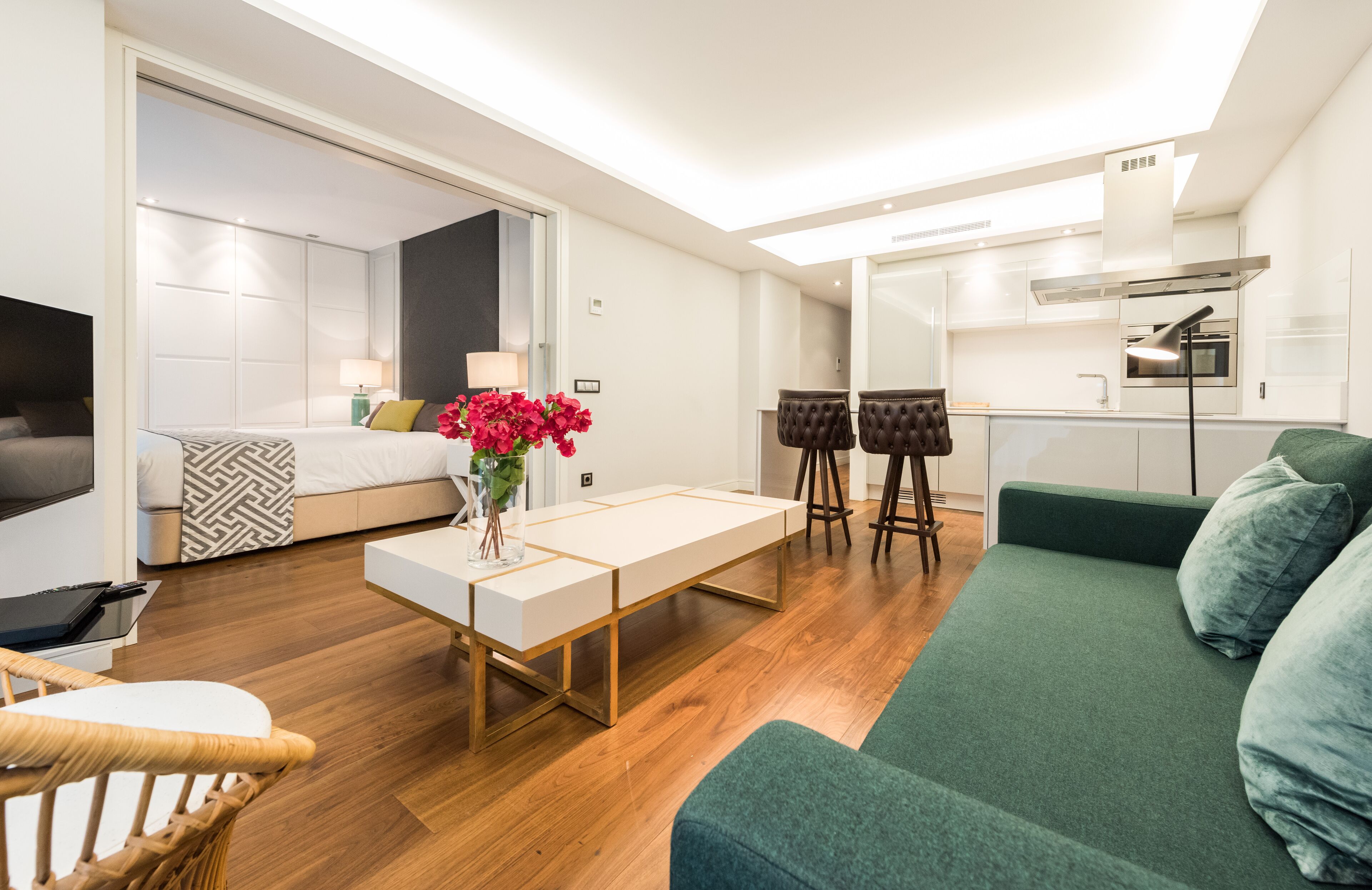 A modern living room with a sofa, a dining table, and a kitchen area in the background.