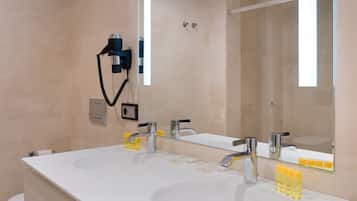 A modern bathroom with two sinks, a large mirror, and a hairdryer on the wall.