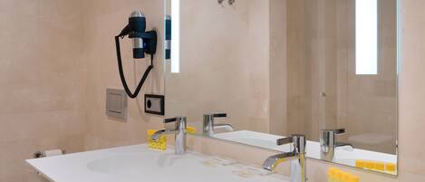 Un baño moderno con dos lavamanos, un espejo grande y un secador de pelo en la pared.