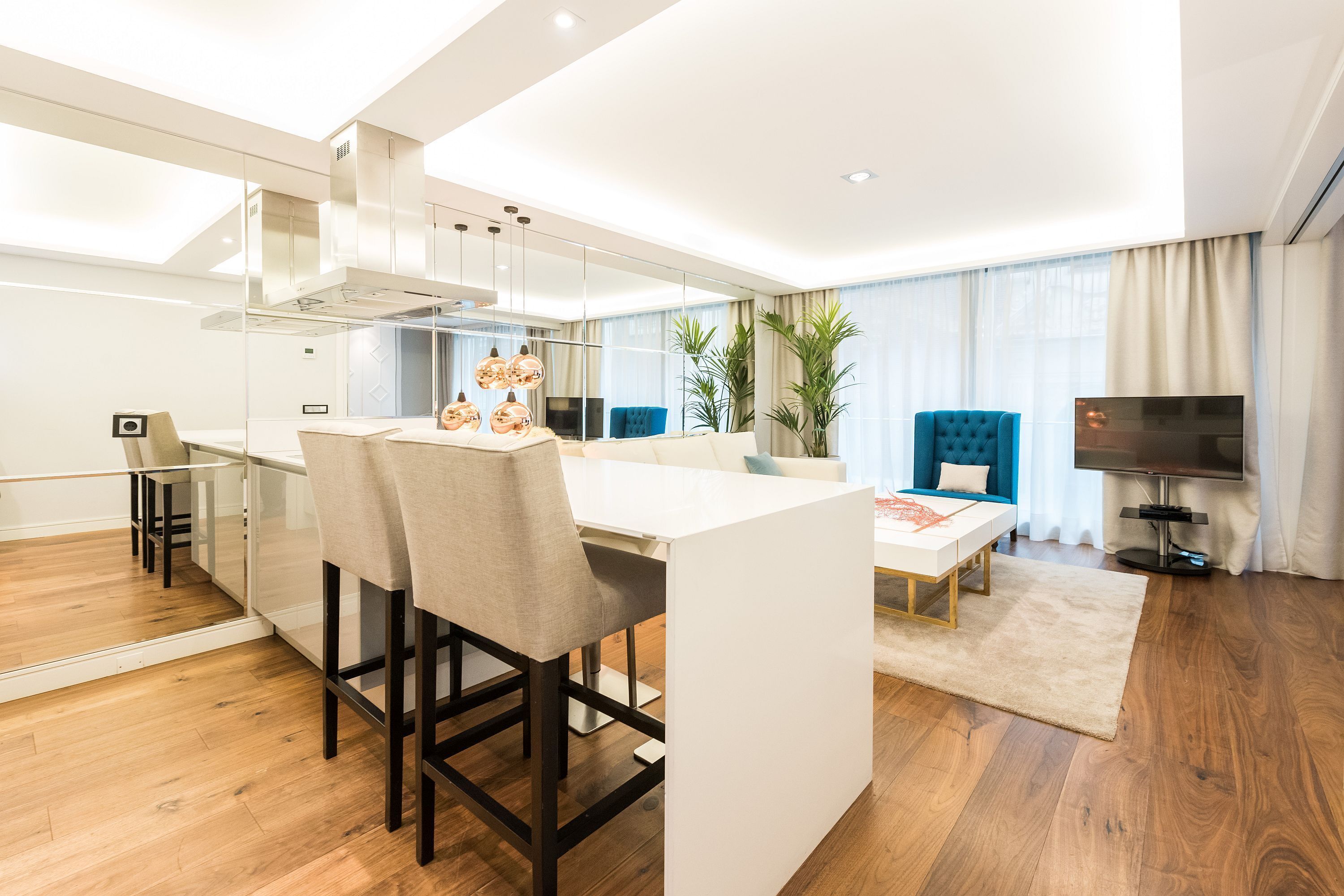A modern living room with a sofa, a TV, and a dining area with a table and chairs.
