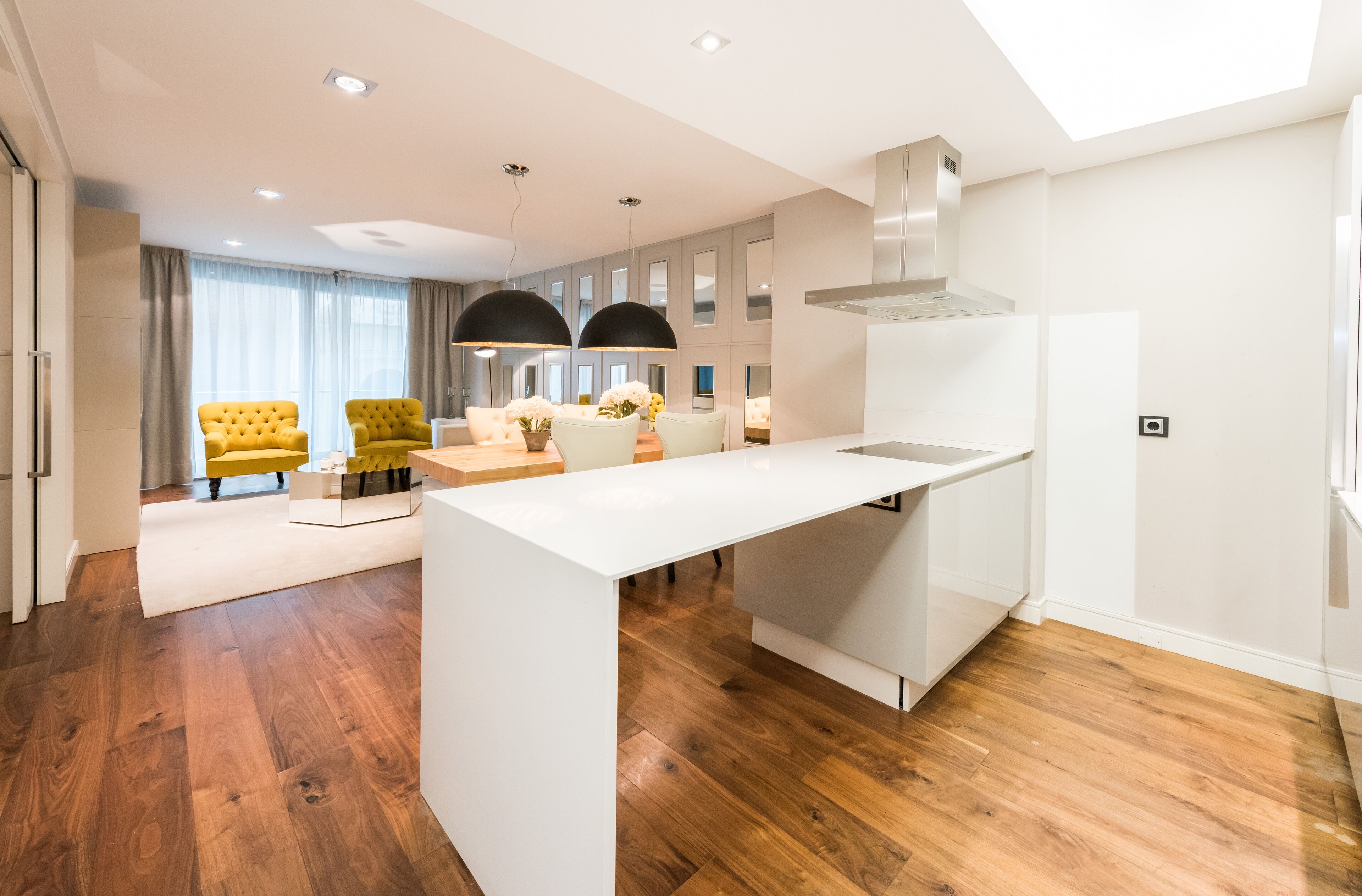 A modern kitchen with white cabinetry, a central island, and pendant lighting.